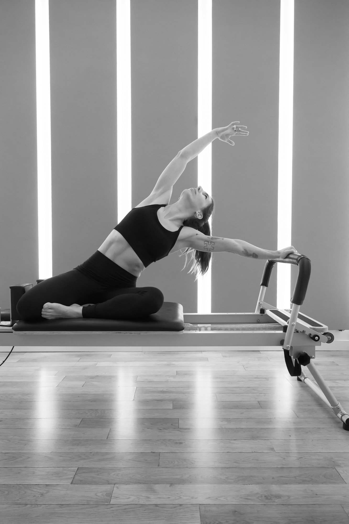 Étirement latéral sur un Reformer, un bras tendu vers le haut